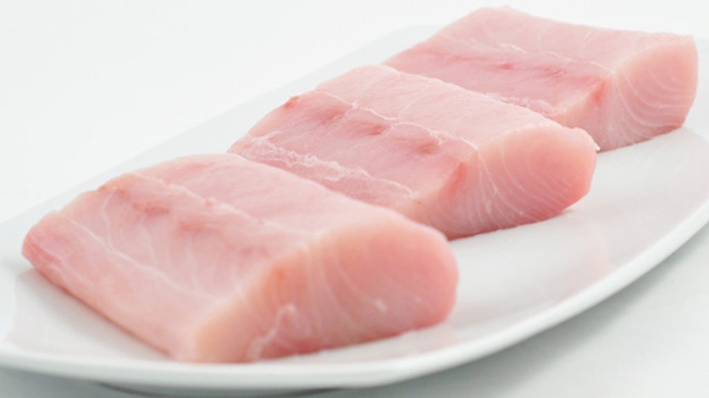 mahi mahi loin portion on plate and white background